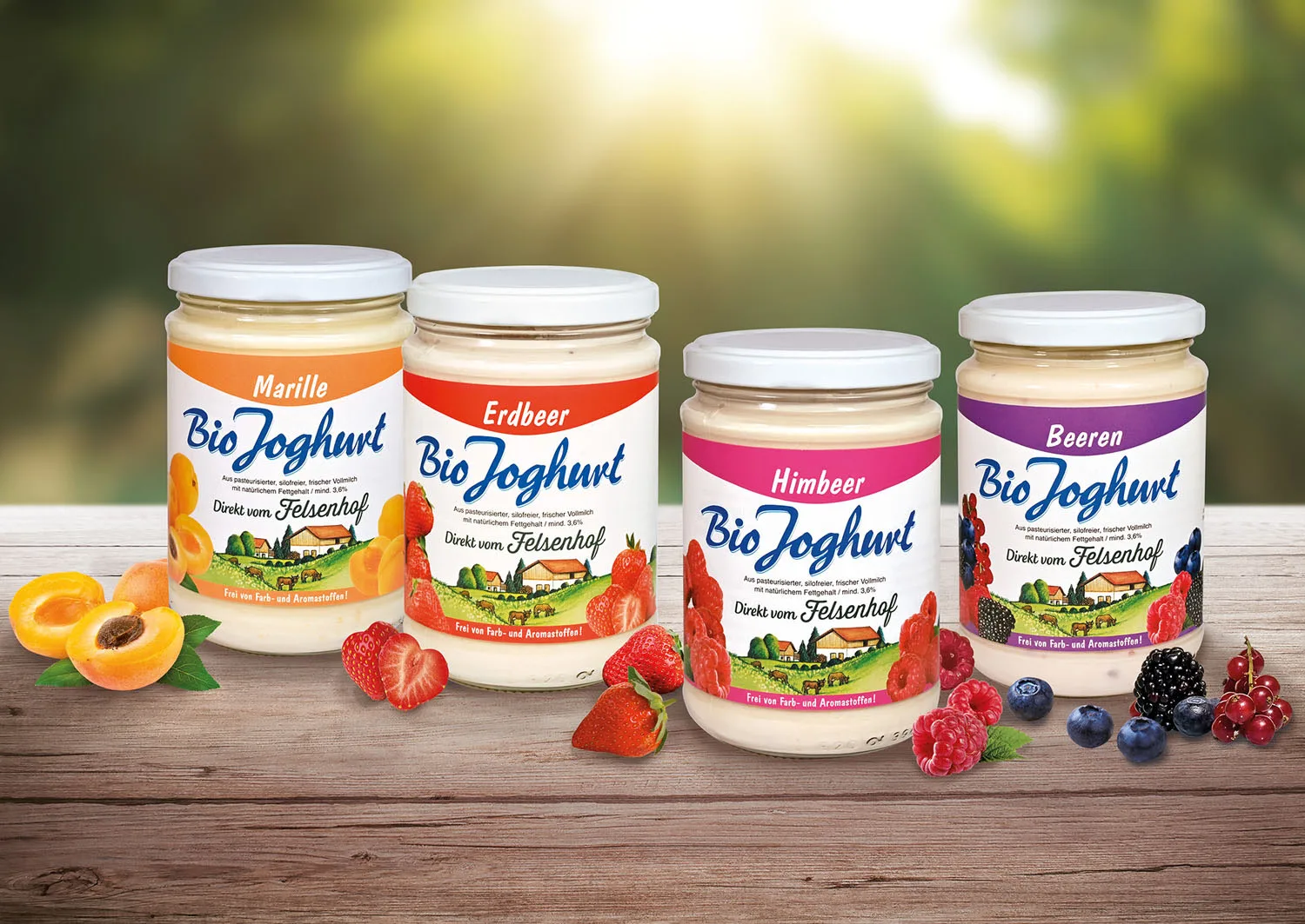 Vier Gläser Bio Joghurt mit Marille, Erdbeere, Himbeere und Beeren auf einem Holzbrett