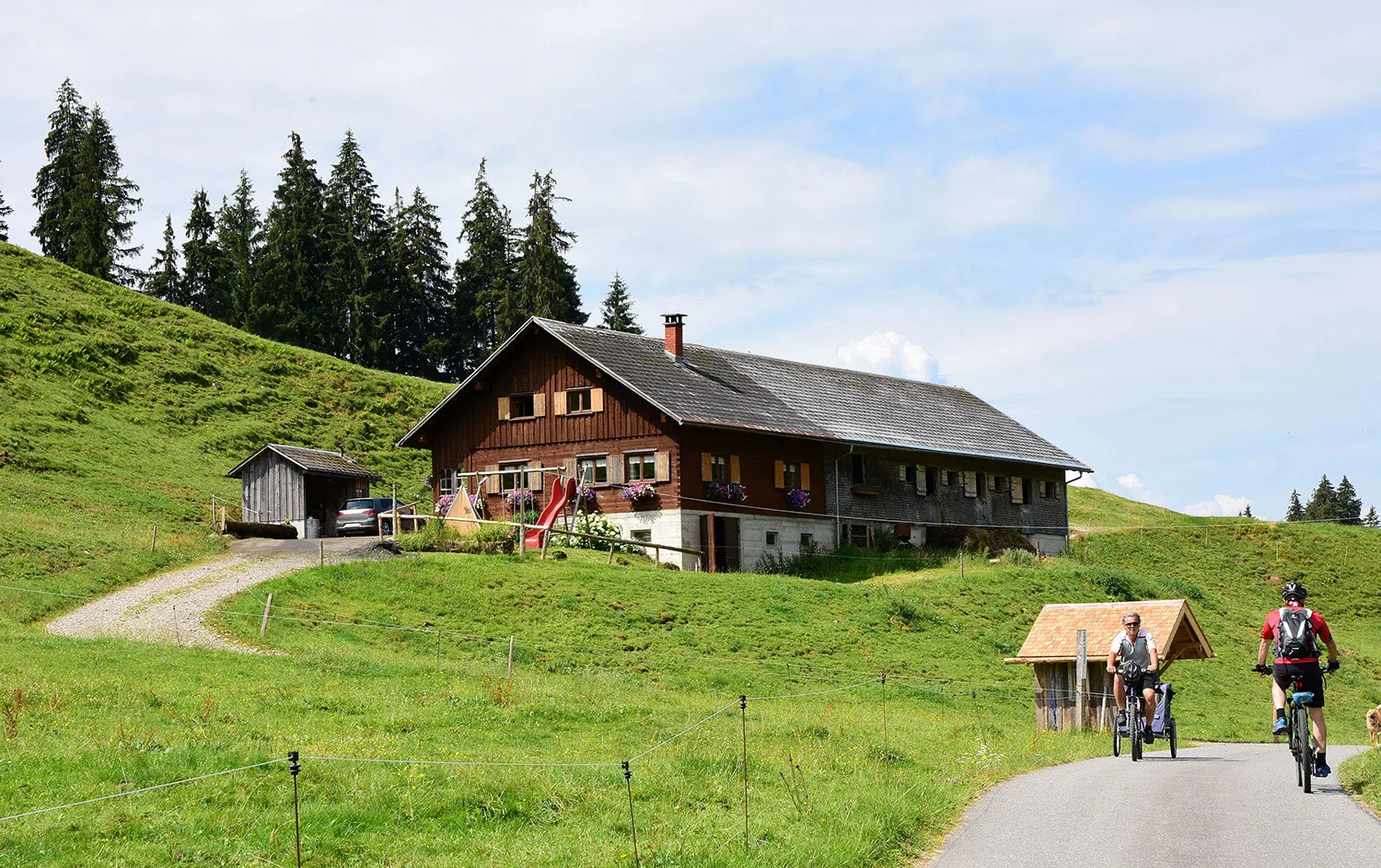 Der Felsenhof von der Straße aus gesehen, davor Radfahrer auf dem Weg